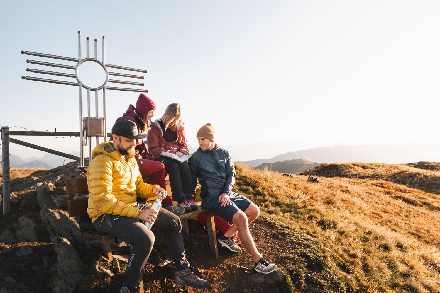 Wandergruppe genießt Pause am Gipfelkreuz